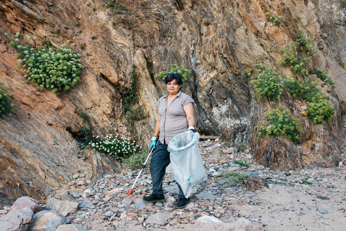 Woman on beach with beach cleaning equipment.