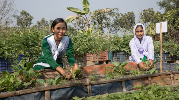 Pallabi, 14 (left) and Razia, 13 (right) tend to their rooftop school garden in Rangpur, Bangladesh